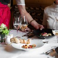 © SPORTALPEN Elegantes Dinner mit liebevoll angerichteten Gerichten, serviert mit zwei Gläsern Weißwein in stilvoller Atmosphär | © SPORTALPEN